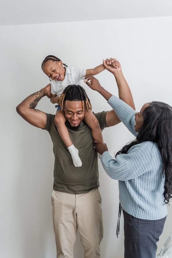 Joyful family bonding indoors as parents lift child, capturing a moment of joy.